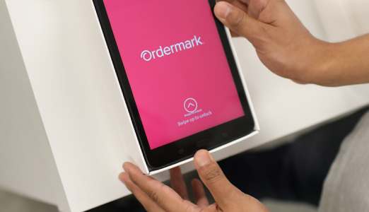 A person holding a tablet with the Ordermark app on screen.
